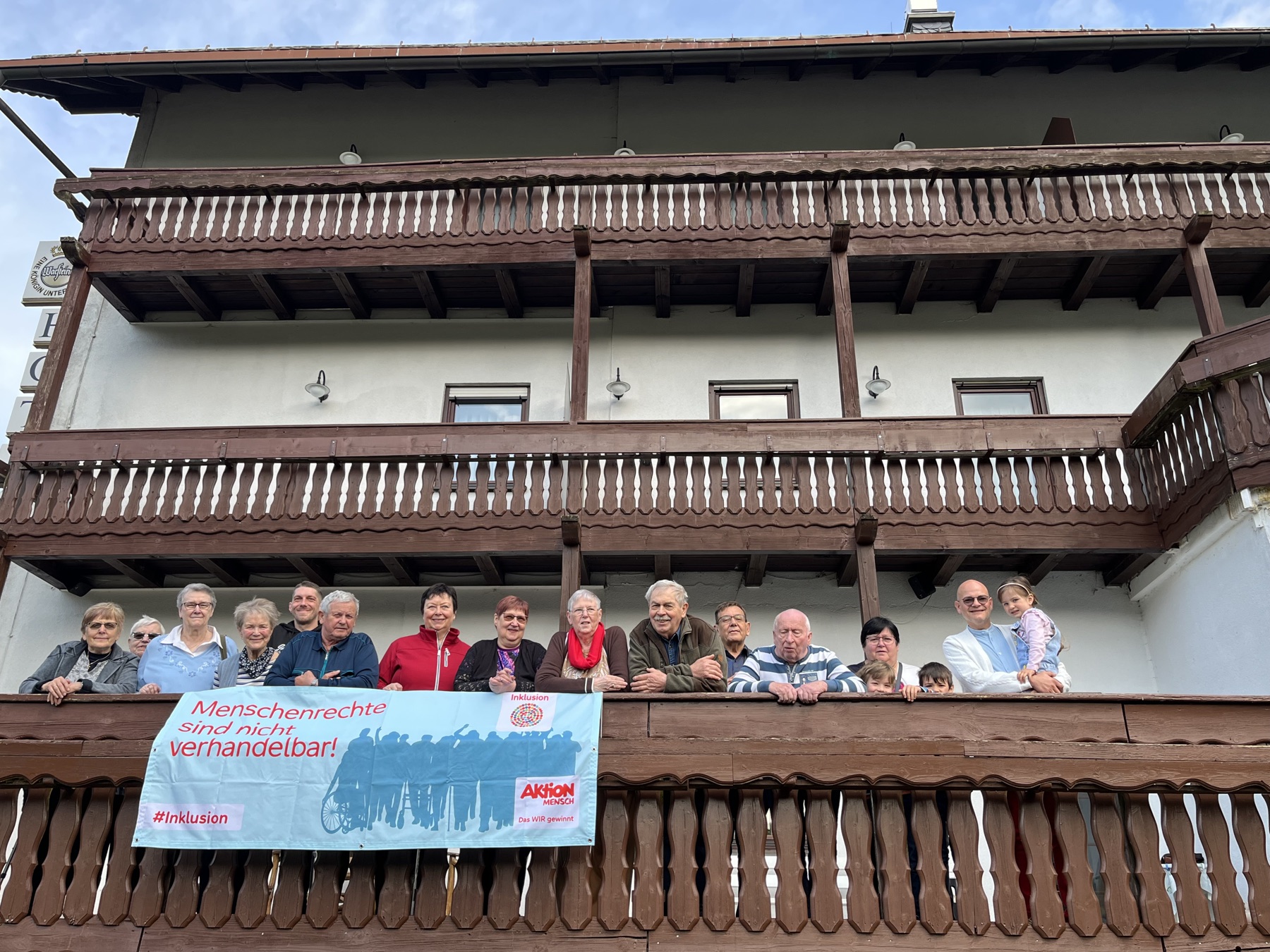Gruppe von Mitgliedern mit einem Banner für Inklusion vor einem Gebäude
